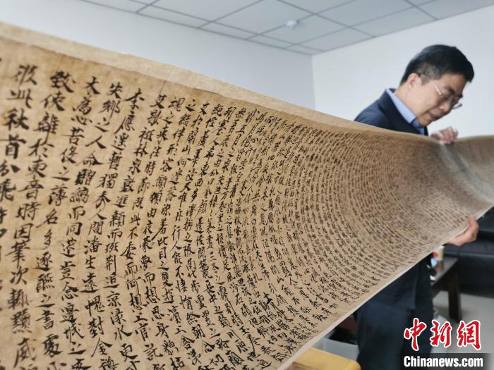 图为读者出版集团敦煌文艺出版社社长展示该社策划出版的《敦煌法藏文献》复制品。(资料图) 闫姣 摄